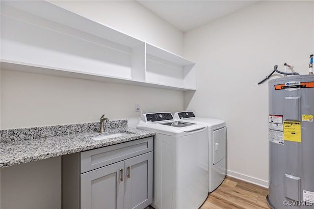 clothes washing area with sink, cabinets, independent washer and dryer, electric water heater, and light hardwood / wood-style floors