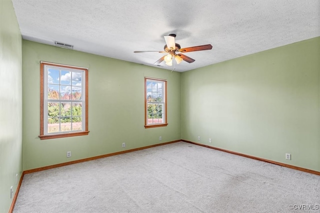 empty room with ceiling fan, a textured ceiling, and light colored carpet