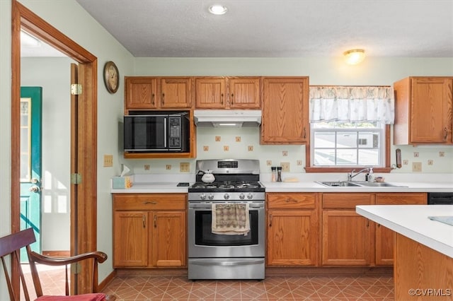 kitchen with sink, stainless steel gas stove, a textured ceiling, and light tile patterned floors