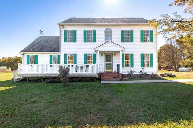 colonial house featuring a front yard and a wooden deck