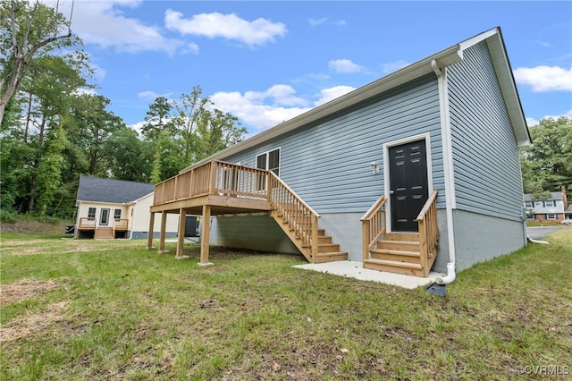 back of property featuring a wooden deck and a lawn