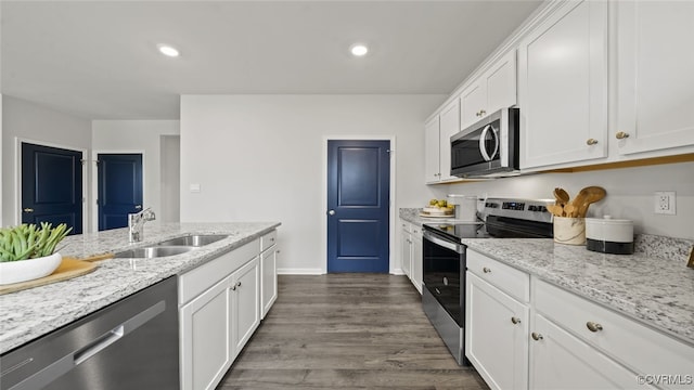 kitchen featuring stainless steel appliances, light stone counters, white cabinets, sink, and dark hardwood / wood-style floors