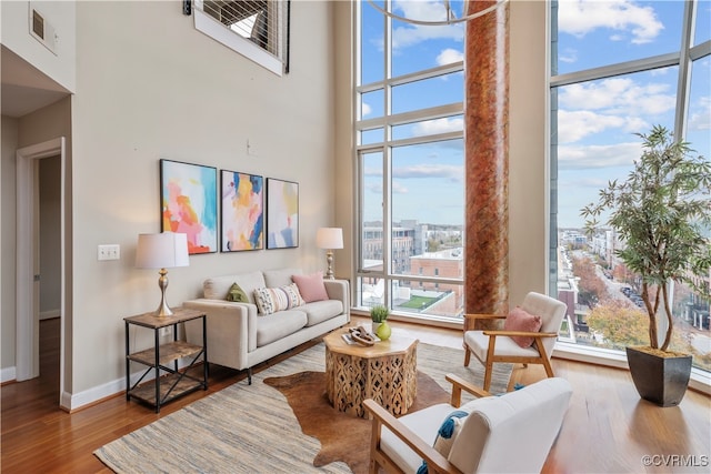 living room with hardwood / wood-style floors, a towering ceiling, and a healthy amount of sunlight