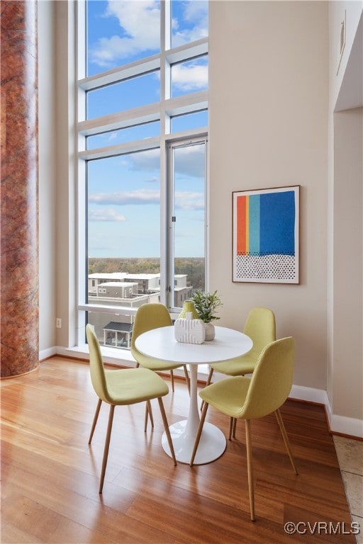 dining area with light wood-type flooring and a towering ceiling