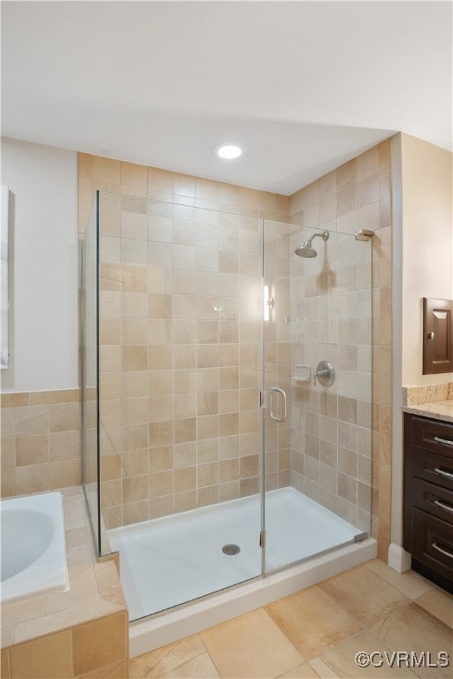 bathroom with tile patterned floors, vanity, and shower with separate bathtub