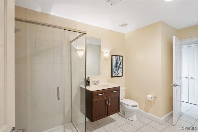 bathroom with tile patterned floors, a shower with door, vanity, and toilet