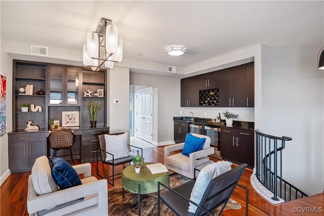 living room with a notable chandelier, sink, and dark wood-type flooring