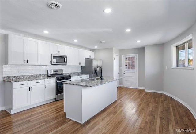 kitchen featuring sink, white cabinetry, a kitchen island with sink, stainless steel appliances, and light wood-type flooring