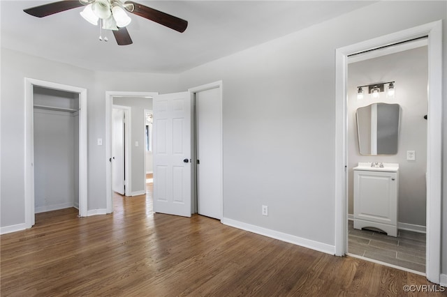 unfurnished bedroom featuring ceiling fan, ensuite bath, and dark hardwood / wood-style flooring