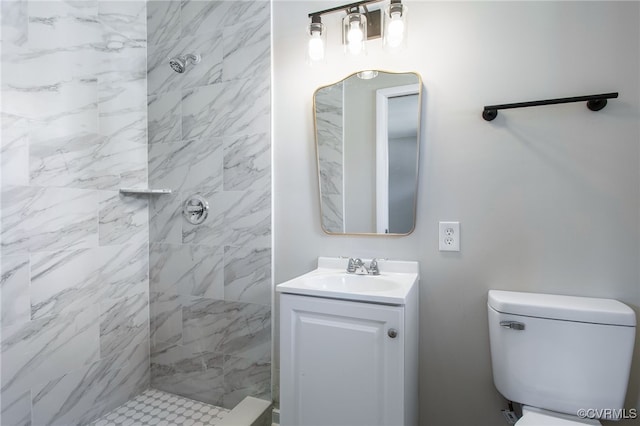 bathroom featuring a tile shower, vanity, and toilet