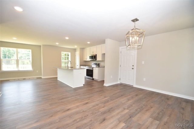 kitchen with pendant lighting, white cabinetry, a center island with sink, appliances with stainless steel finishes, and dark hardwood / wood-style flooring