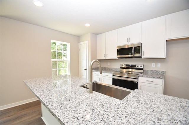 kitchen featuring white cabinets, dark wood-type flooring, stainless steel appliances, and light stone counters