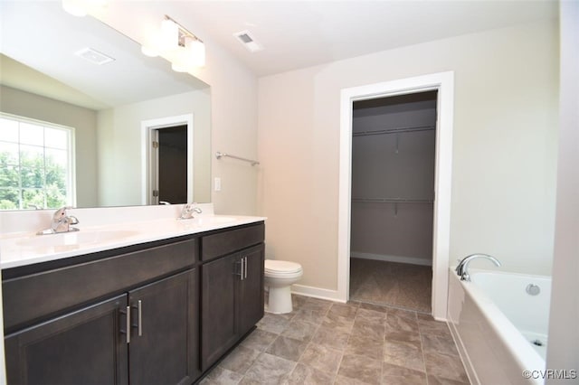 bathroom featuring tiled bath, vanity, and toilet