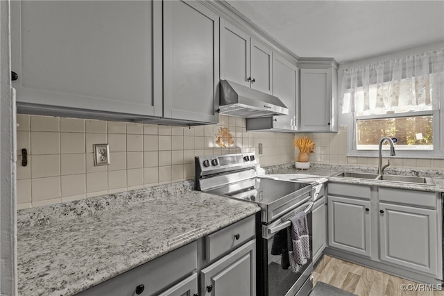 kitchen with stainless steel range with electric cooktop, sink, gray cabinets, light wood-type flooring, and tasteful backsplash