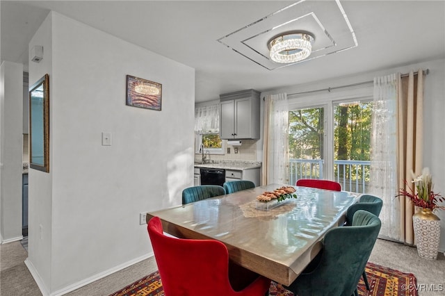 dining area with sink, light colored carpet, and an inviting chandelier