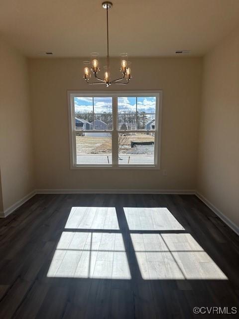 unfurnished dining area with a notable chandelier and dark wood-type flooring