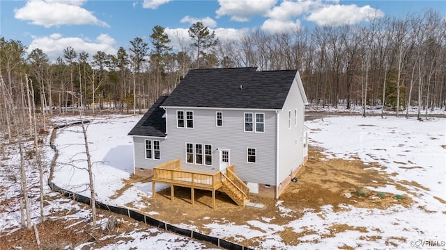 snow covered rear of property with a deck