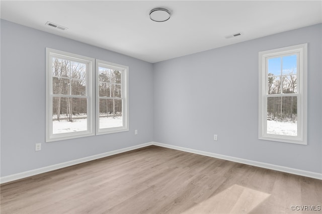 spare room featuring light hardwood / wood-style floors and a healthy amount of sunlight