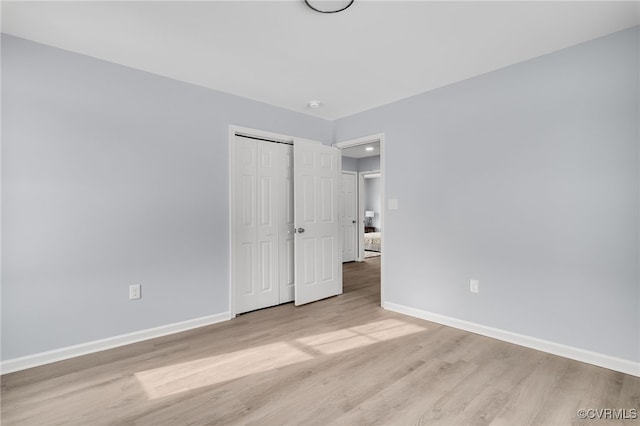 unfurnished bedroom with light hardwood / wood-style flooring and a closet