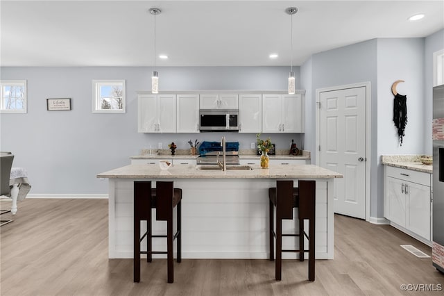 kitchen featuring a breakfast bar, decorative light fixtures, white cabinetry, and appliances with stainless steel finishes