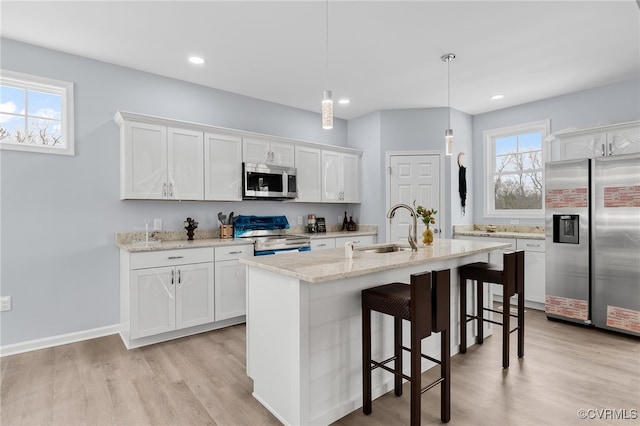 kitchen featuring appliances with stainless steel finishes, white cabinetry, pendant lighting, and sink