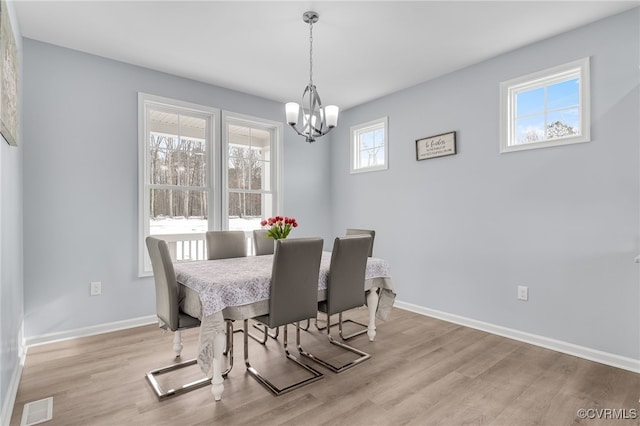 dining area with light hardwood / wood-style floors and a notable chandelier