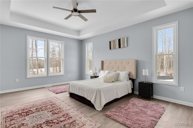 bedroom with a tray ceiling, ceiling fan, and light hardwood / wood-style floors