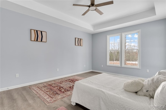 bedroom featuring hardwood / wood-style floors, ceiling fan, and a tray ceiling