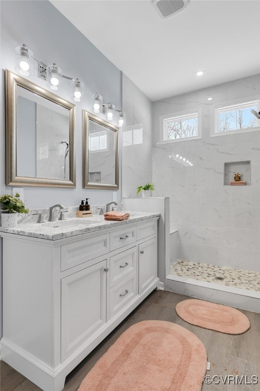 bathroom with a tile shower, vanity, and hardwood / wood-style flooring