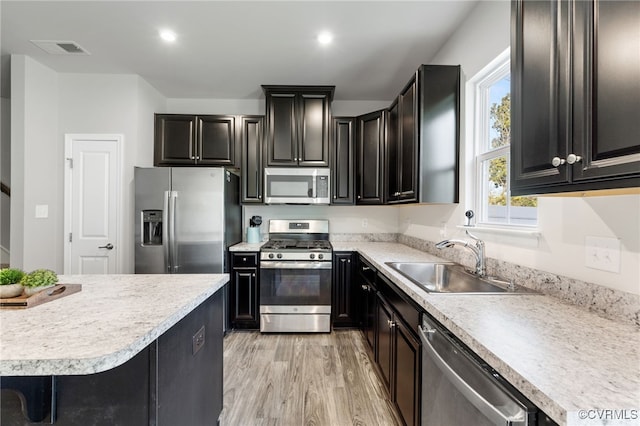 kitchen featuring appliances with stainless steel finishes, sink, a breakfast bar area, and light wood-type flooring