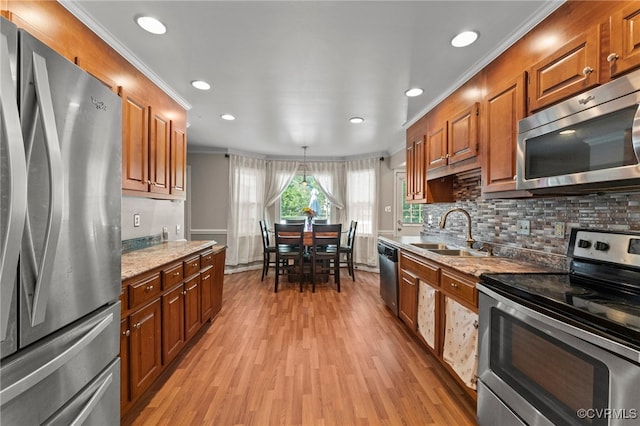 kitchen featuring light wood-type flooring, ornamental molding, sink, appliances with stainless steel finishes, and light stone countertops