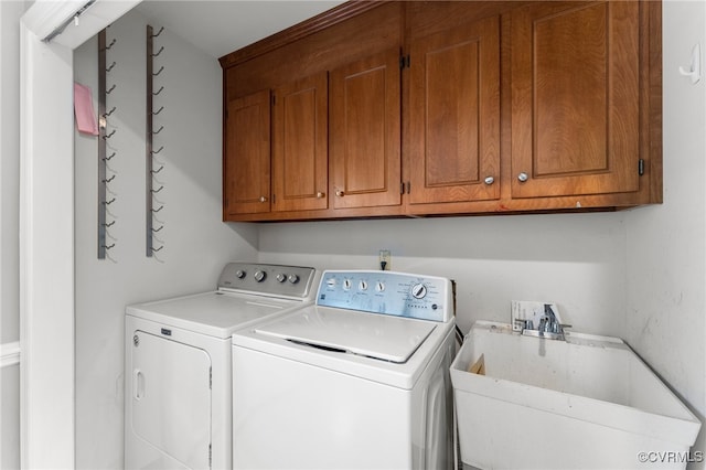 clothes washing area featuring washing machine and clothes dryer, sink, and cabinets