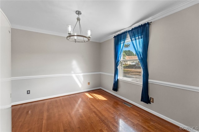 empty room with ornamental molding, hardwood / wood-style floors, and a chandelier