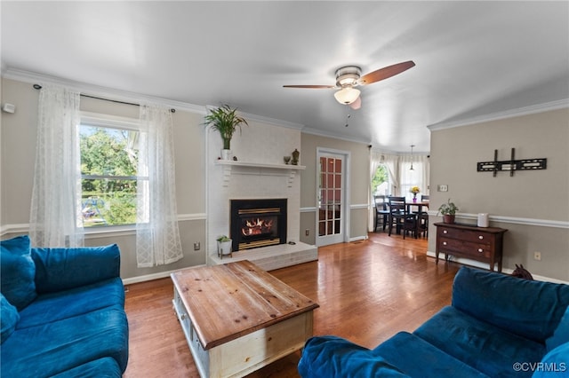 living room with ceiling fan, a brick fireplace, hardwood / wood-style flooring, and plenty of natural light