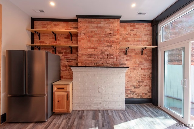 interior space with wood-type flooring, brick wall, crown molding, and stainless steel fridge