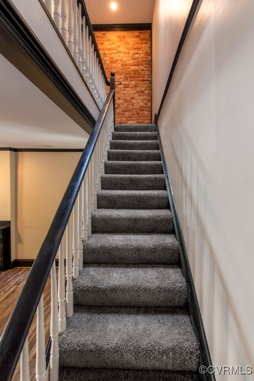 stairs with hardwood / wood-style floors and crown molding