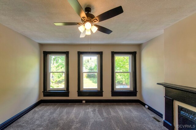 unfurnished living room featuring ceiling fan, a textured ceiling, and dark colored carpet