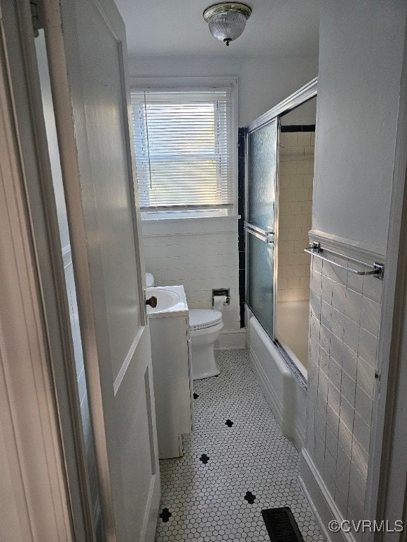 full bathroom with vanity, tile walls, tile patterned floors, and shower / bath combination with glass door