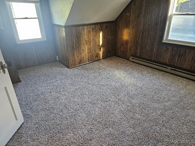 bonus room with baseboard heating, wooden walls, and a wealth of natural light