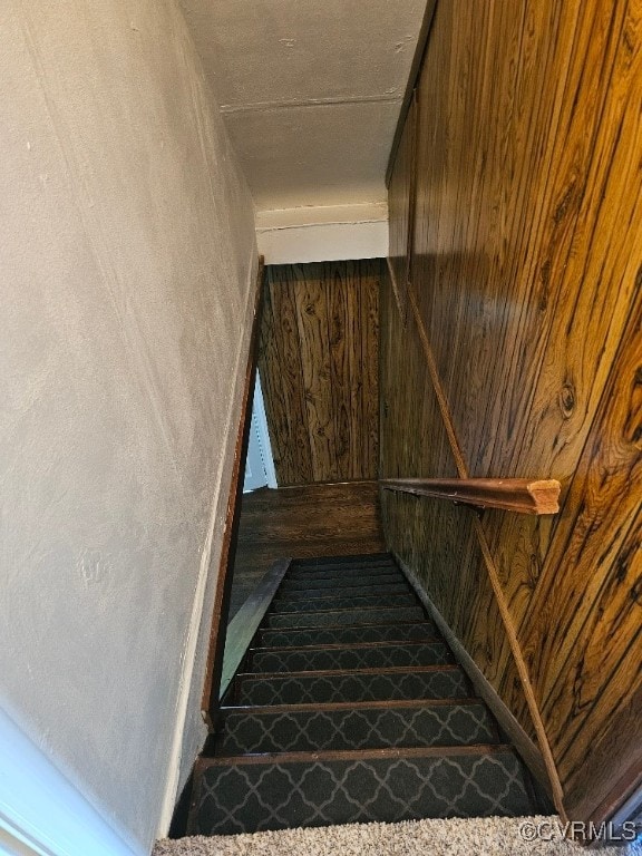 stairway featuring wooden walls