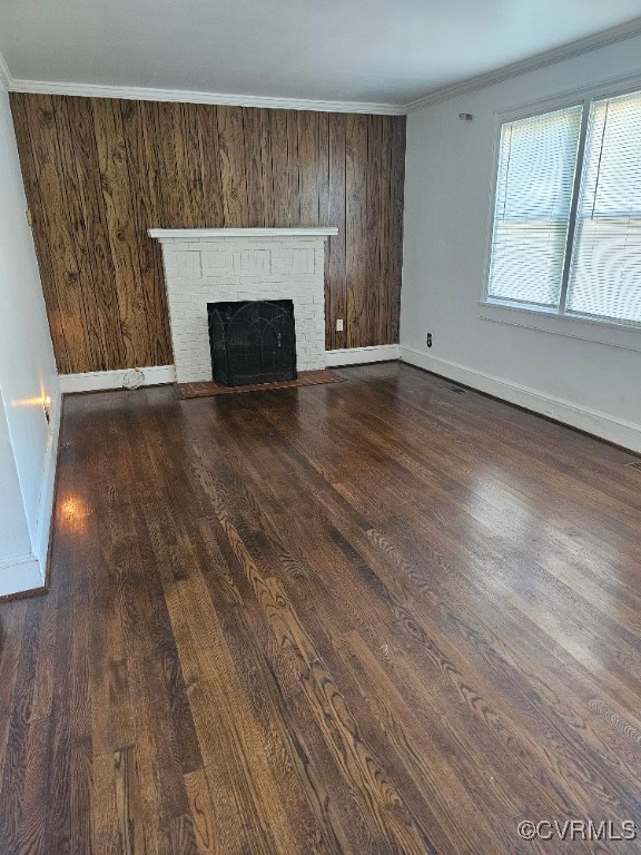 unfurnished living room with ornamental molding, a brick fireplace, and dark wood-type flooring