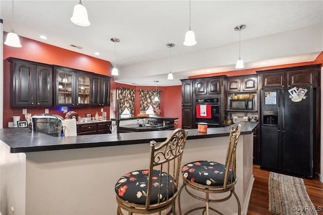 kitchen featuring black appliances, dark brown cabinetry, a breakfast bar area, and dark hardwood / wood-style flooring