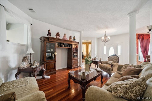 living room featuring dark wood-type flooring, an inviting chandelier, decorative columns, and a textured ceiling