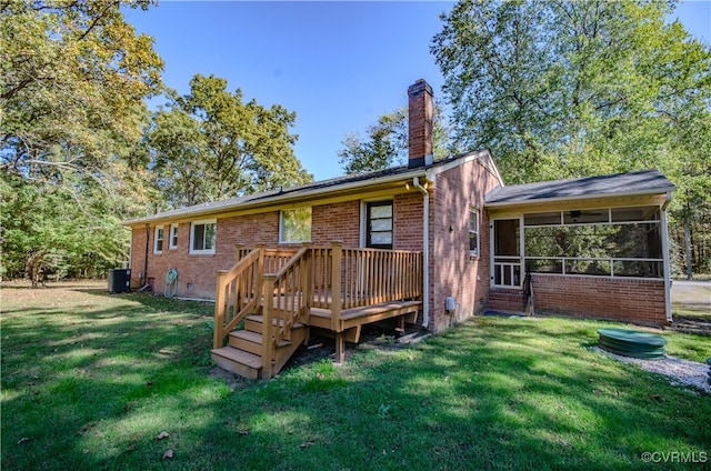 rear view of house featuring a sunroom, a deck, a lawn, and central AC