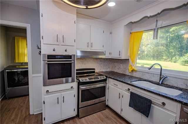 kitchen featuring appliances with stainless steel finishes, white cabinetry, washer / dryer, and backsplash