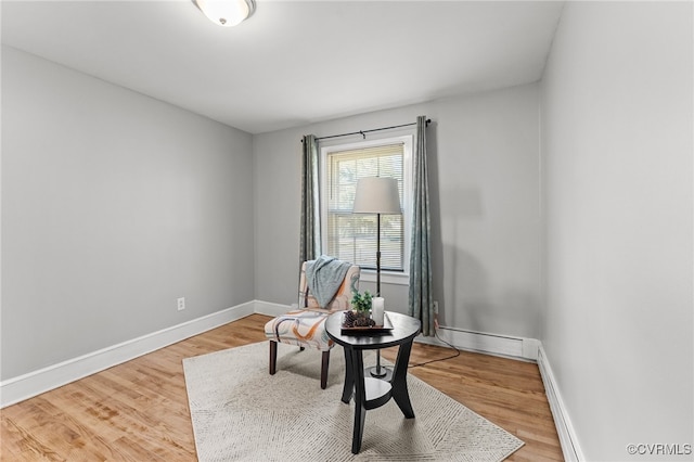 living area with hardwood / wood-style floors and a baseboard heating unit