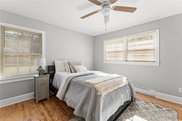 bedroom with baseboard heating, light wood-type flooring, and ceiling fan