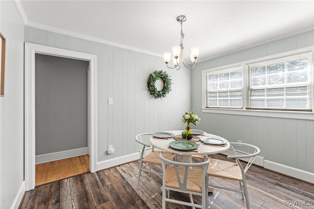 dining space featuring an inviting chandelier, ornamental molding, wooden walls, and dark hardwood / wood-style flooring