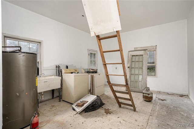 washroom with independent washer and dryer, water heater, and sink