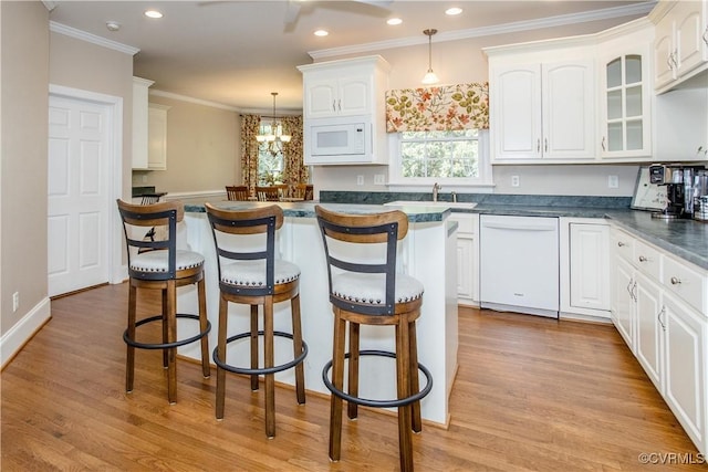 kitchen with a breakfast bar, dark countertops, white appliances, and white cabinetry